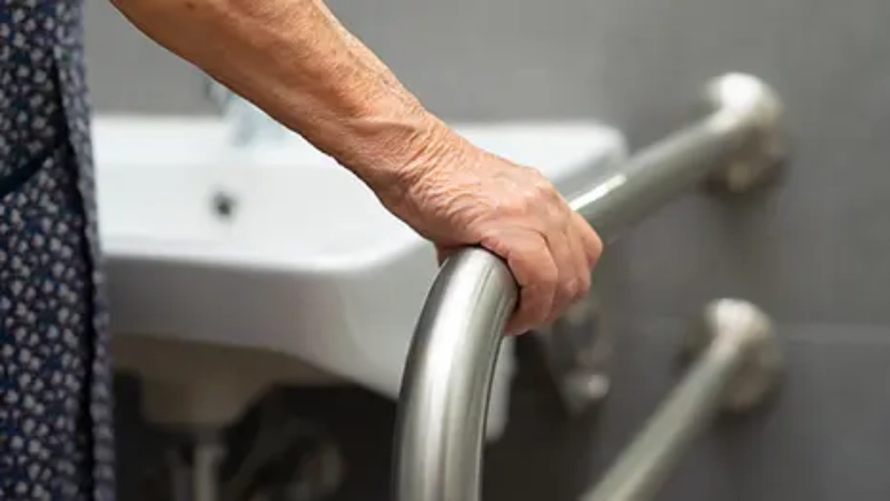 Une personne attrape une barre de soutien à côté d'un lavabo pour se maintenir en équilibre
