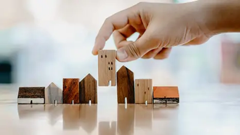 main posant des mini constructions en bois sur un sol