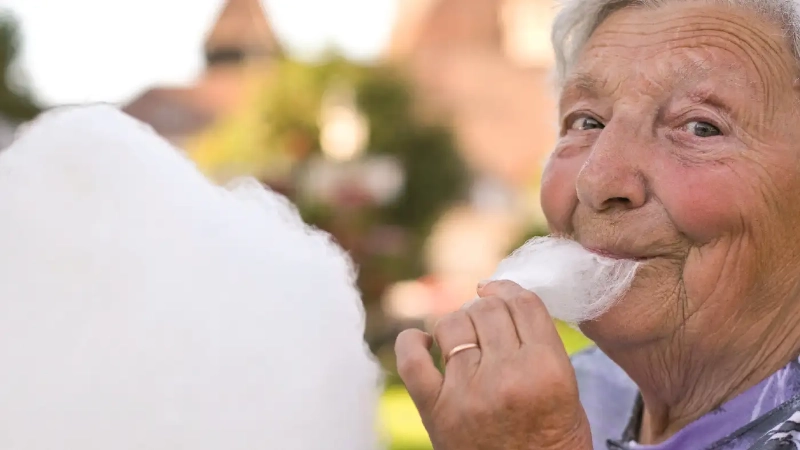 Dame âgée qui mange une barbe à papa