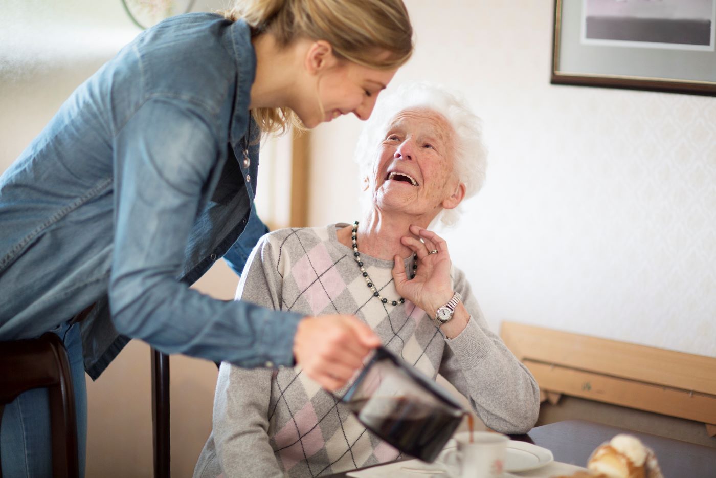 Mitarbeitende schenkt Seniorin Kaffee ein. 