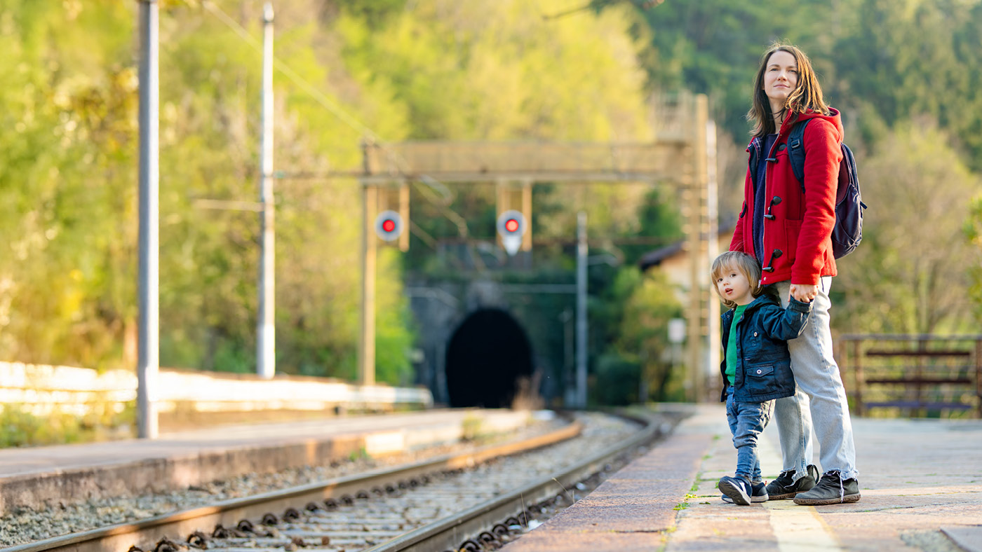 Une femme se tient avec son fils sur le quai et attend le train