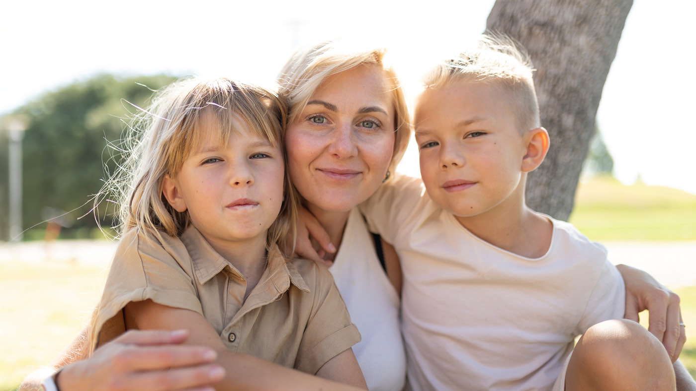 Une femme avec deux enfants regarde l'appareil photo